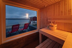 Una cabaña de madera con un ventanal grande que da a un cuerpo de agua y un pequeño muelle.