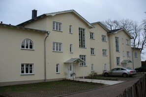 A multi-story residential building with a flat roof, multiple windows, and a paved driveway. - Holiday apartment with 2 bedrooms (Sassnitz)