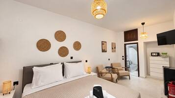 Une chambre d’hôtel avec un lit, un bureau, une chaise, une télévision et une salle de bain visible à travers une porte ouverte.