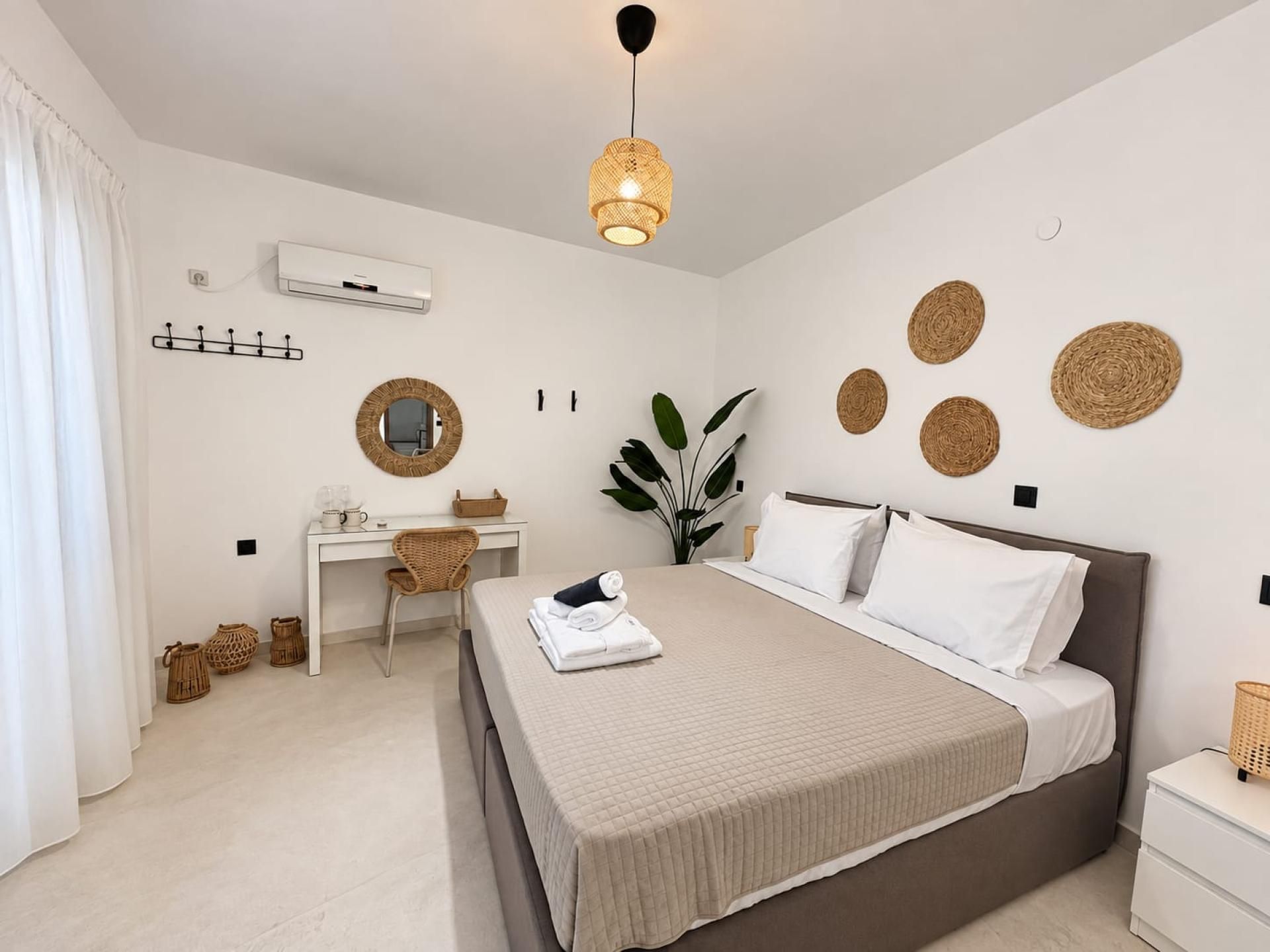 Un dormitorio moderno con cama, escritorio y lámpara colgante.