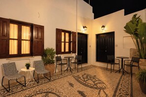 A courtyard with a tiled floor, wooden doors, and two tables with chairs. - Eternel Room 2 in Lindos (Rhodes)