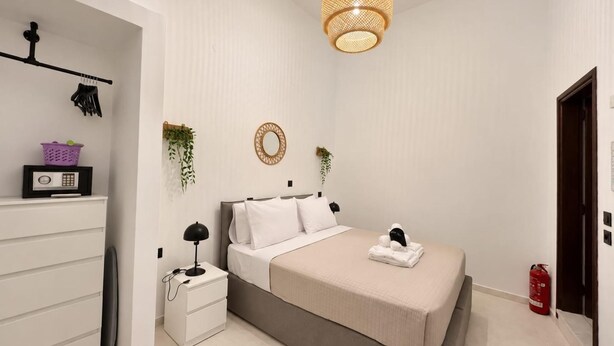 Ein Schlafzimmer mit Bett, Nachttisch, Lampe und einer Pendelleuchte.