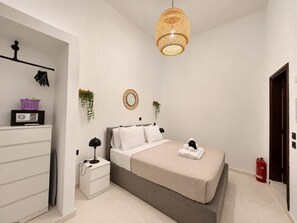 Een slaapkamer met een bed, nachtkastje, lamp en een hangende lamp.