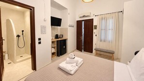 Ein Hotelzimmer mit Bett, Dusche, Fernseher, Schreibtisch und einer Sitzbank.