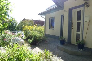 A building with a number 31 on the door, a paved entrance area, and potted plants. - House by the Pirate Gorge (Sassnitz)