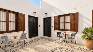 A courtyard with two doors, a table with chairs, and a potted plant.
