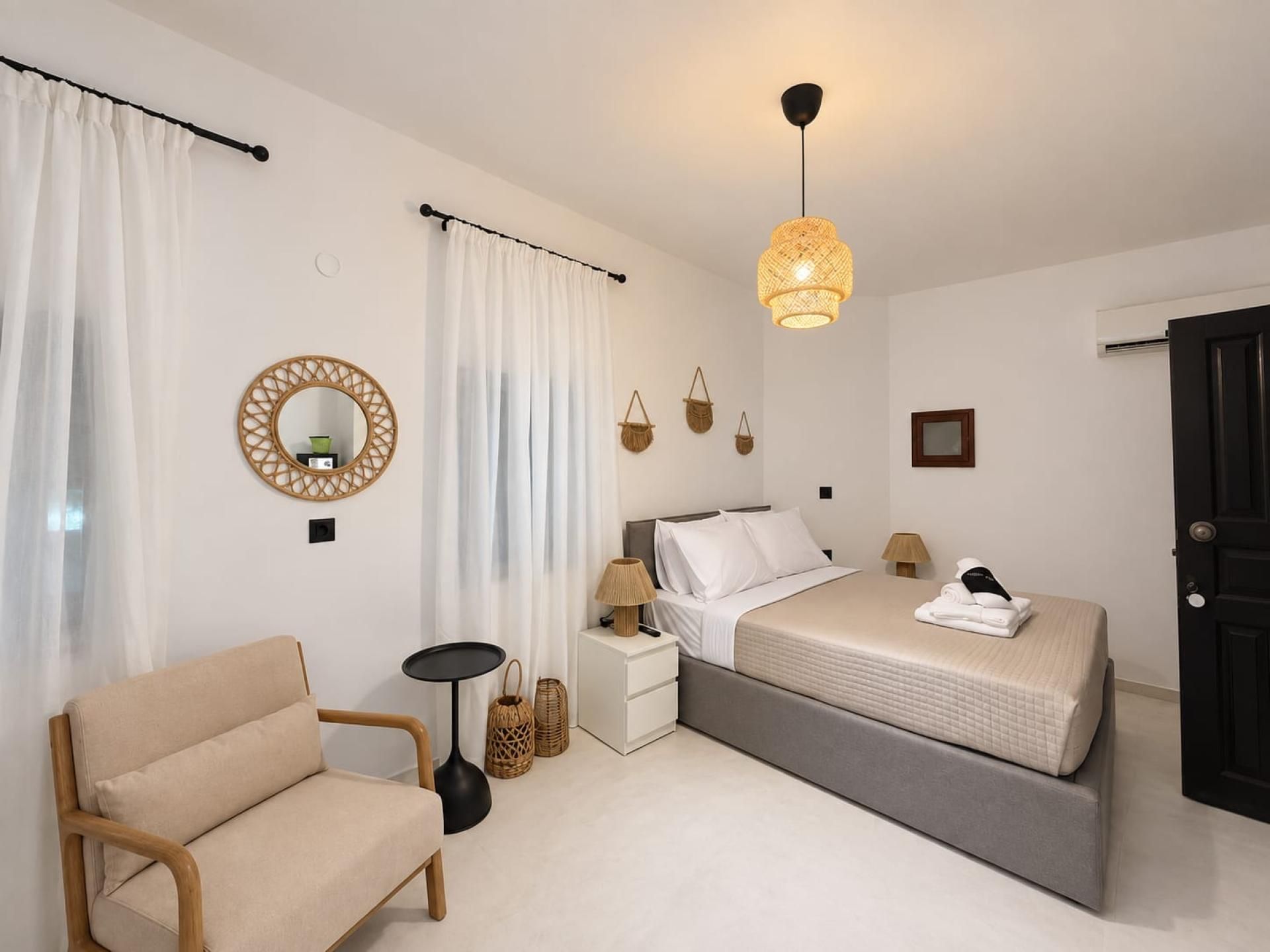 Une chambre à coucher comprenant un lit, des tables de chevet, une chaise, une lampe et un luminaire suspendu.