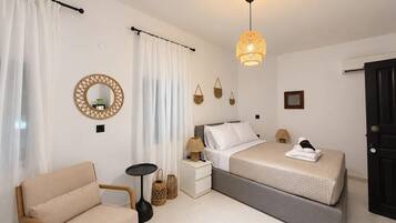 Une chambre à coucher comprenant un lit, des tables de chevet, une chaise, une lampe et un luminaire suspendu.