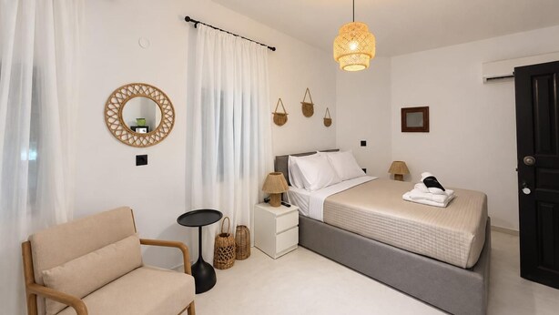Ein Schlafzimmer mit einem Bett, Nachttischen, einem Sessel, einer Lampe und einer Pendelleuchte.