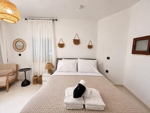 A hotel room with a bed, a chair, a lamp, and wall decorations. - Eternel Room 4 in Lindos (Rhodes)