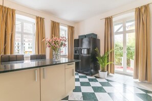 A kitchen with a black refrigerator, a marble countertop, and a checkered floor. - Apartment House Saxonia (Bad Schandau)