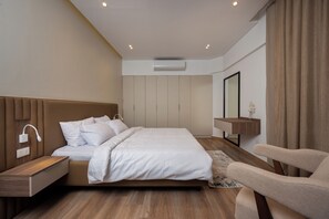 Ein modernes Schlafzimmer mit einem Bett, Nachttischen, einem Spiegel und einem Sessel.