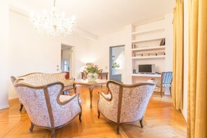 Ein geräumiges Wohnzimmer mit einer Kandelaber, einem runden Couchtisch und einem Bücherregal.