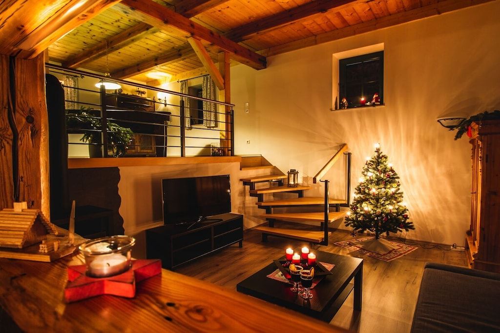 A cozy living room with a fireplace, a staircase, and a decorated Christmas tree.