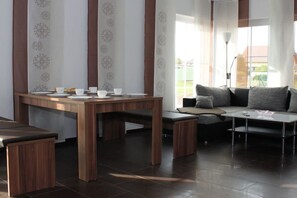 A modern living space with a wooden dining table, a sofa, and a small coffee table. - Holiday home Stein in the Spreewald Lübbenau (Lübbenau)