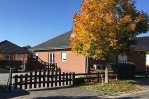 A residential building with a brick facade, a gated entrance, and a tree with autumn foliage. - Holiday home Stein in the Spreewald Lübbenau (Lübbenau)