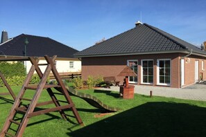 A residential property with a brick house, a wooden swing set, and a paved driveway. - Holiday home Stein in the Spreewald Lübbenau (Lübbenau)