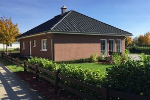 A single-story brick building with a dark roof, a small porch, and a wooden fence. - Holiday home Stein in the Spreewald Lübbenau (Lübbenau)