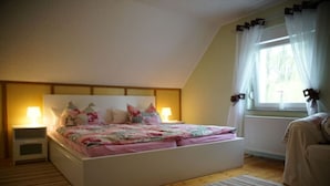 A bedroom with a bed, bedside tables, a window with curtains, and a radiator. - Holiday home in Lübben with swimming pool (Lübben)