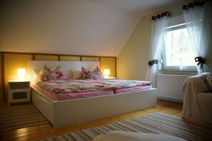 Un dormitorio con cama, mesitas de noche, una ventana con cortinas y un radiador.
