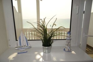 Uma planta em vaso numa varanda com vista para o mar.