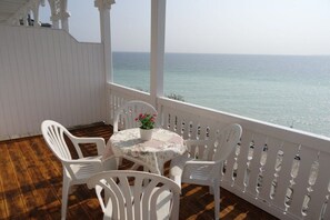 Un espace extérieur abrité, avec une table et des chaises, offrant une vue sur la mer.
