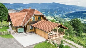 A wooden house with a sloped roof, a garage, and a covered porch. - Kogljahrerhütte || Prebl (Prebl)