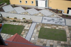 Ein Innenhof mit befestigtem Bereich, einem kleinen Garten und einem Gebäude mit gelber Fassade.