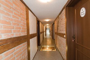 Ein Korridor mit Backsteinwänden, einer Holztür mit Namensschild und einem Fliesenboden.