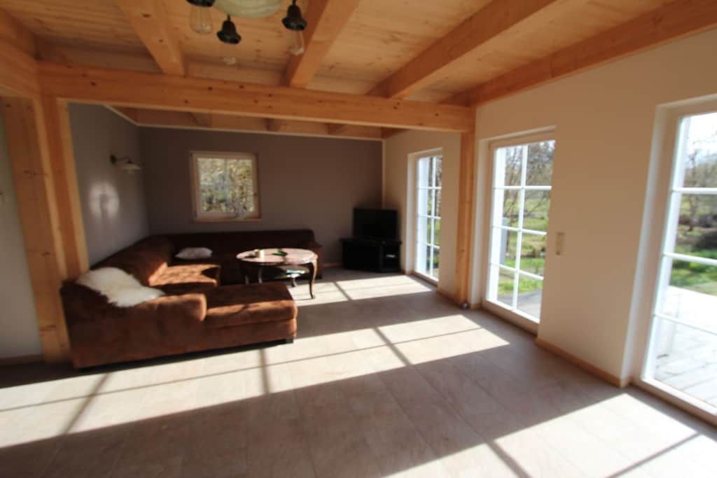 A spacious living room with a brown sofa, a small round table, and a painting on the wall.