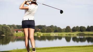 A person playing golf on a course with a body of water in the background.