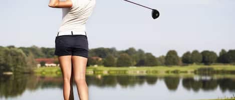 Une personne jouant au golf sur un parcours avec une étendue d'eau en arrière-plan.