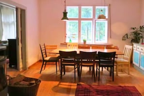 A dining area with a table and chairs, a window with natural light, and a plant on the windowsill.