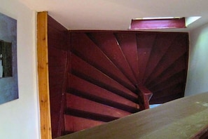 Eine Wendeltreppe mit hölzernem Geländer und einer dunklen Wand.