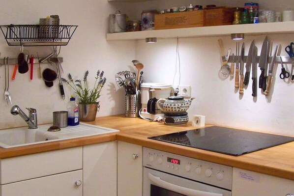 Una cocina con un lavamanos, estufa y varios utensilios colgados en la pared.