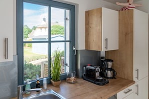 Eine Küche mit großem Fenster, einer Kaffeemaschine und einem Blumentopf.
