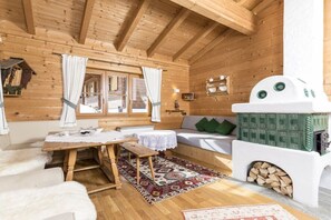 A cozy cabin interior with wooden walls, a sofa, a table, and a fireplace.