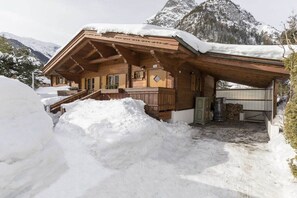 A wooden chalet with a snow-covered roof, a wooden staircase, and a mountain backdrop. - Alpine chalet Achensee (Maurach am Achensee)