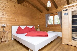 A wooden cabin room with a bed, a nightstand, a lamp, and a window with curtains. - Alpine chalet Achensee (Maurach am Achensee)