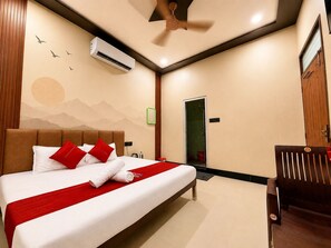 Ein Hotelzimmer mit einem Bett, einer Klimaanlage, einem Deckenventilator, einer Dusche und einer Sitzecke.