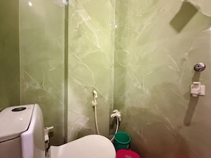 A bathroom with a toilet, a shower, and a green marble wall. - Hotel JSR Inn (Mathura)