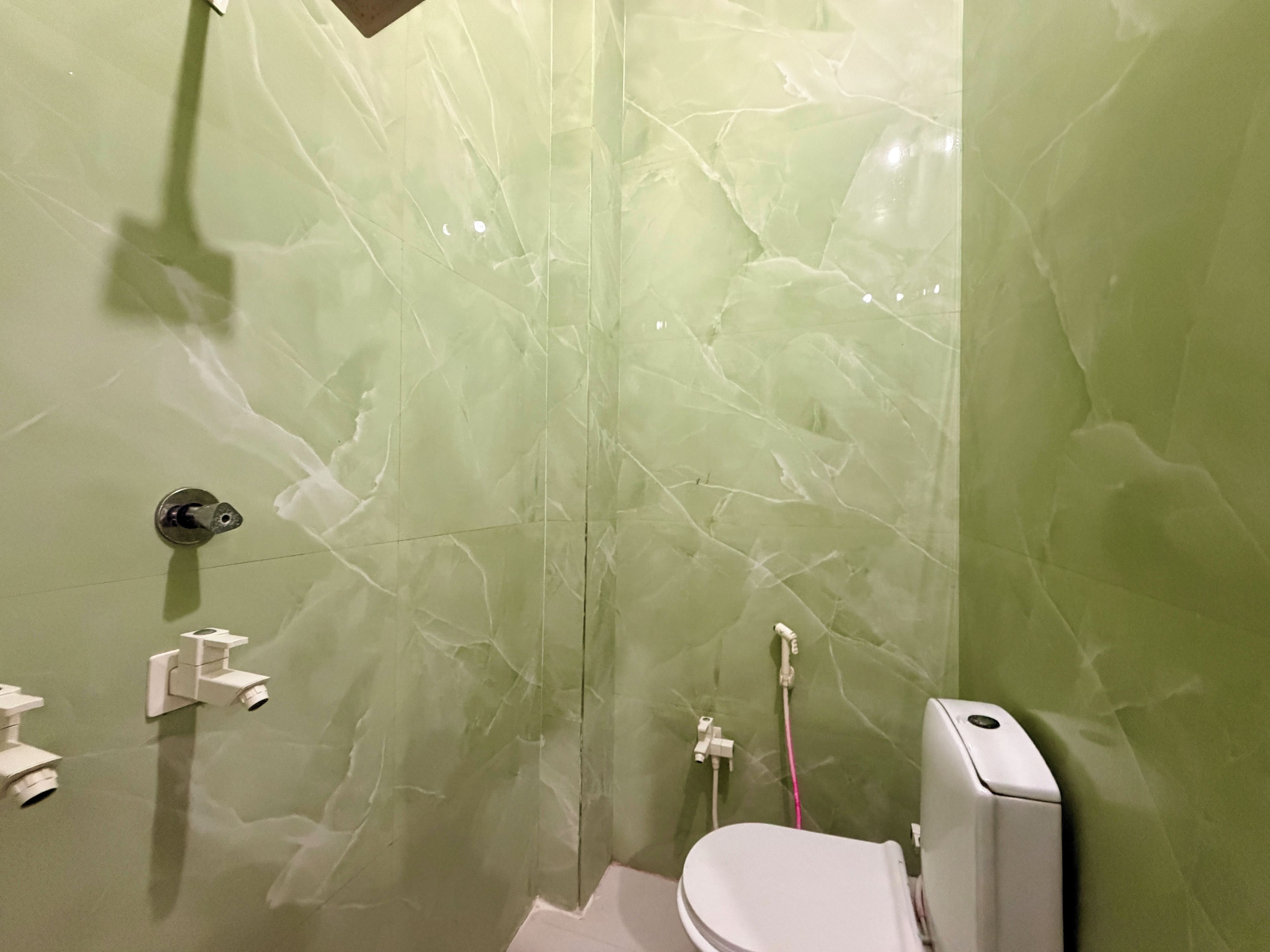 A bathroom with a toilet, a shower, and a hand dryer.