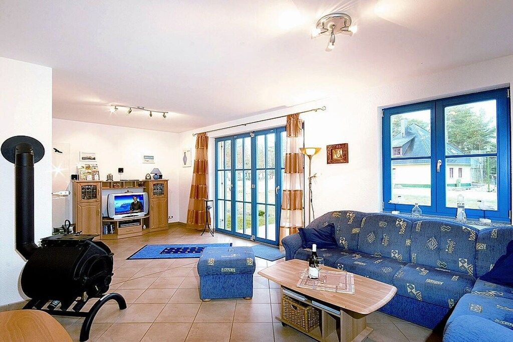 Ein Wohnzimmer mit einer Couch, einem Fernseher, einem Kamin und einem großen Fenster.