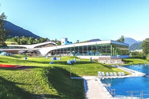 A modern building with a glass facade, a pool, and a landscaped area with lounge chairs. - Tyrolean charm in the Stubai Valley - NEW! (Telfes im Stubai)