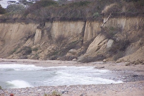 A coastal landscape with a sandy beach, rocky cliffs, and sparse vegetation. - Holiday home in Lancken with swimming pool (Lancken)