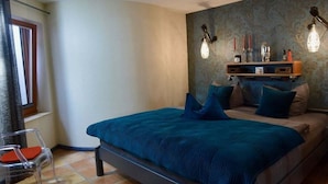 A bedroom with a bed, a chair, a shelf with items, and a patterned wall. - Holiday apartment in Waren with swimming pool (Waren)