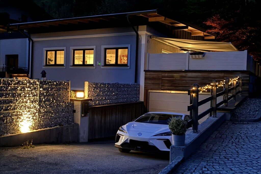 A modern house with a white exterior, a garage, and a white car parked in the driveway.