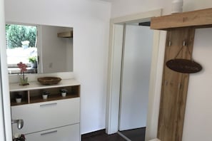 A bathroom with a white vanity, a mirror, a wooden shelf with a sign, and a door leading to another room. - Holiday apartment family Glanznig (Werfen)