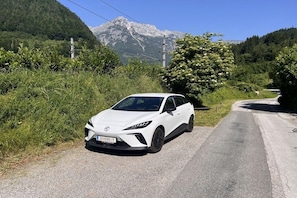 A white car parked on a road with a mountainous backdrop. - Holiday apartment family Glanznig (Werfen)