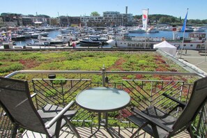 Una terraza con mesa y sillas con vista a un puerto deportivo y barcos.